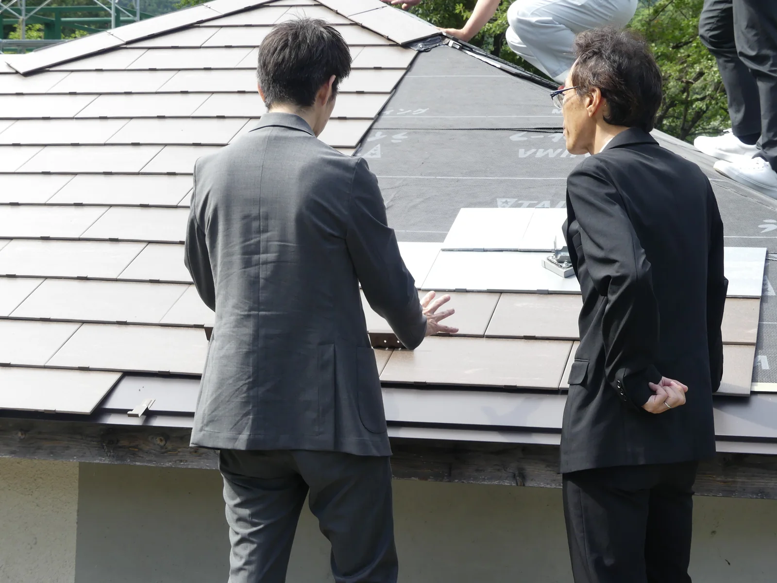 屋根施工現場でタイルーフの納まりを確認する技術者